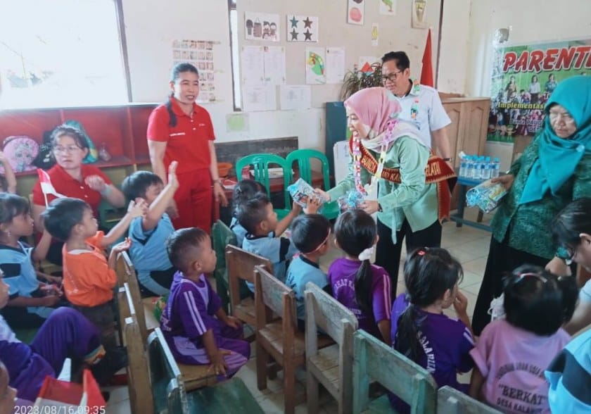 Bunda PAUD Kab.Barsel Hj. Erna Ardiani membagikan bingkisan kepada anak-anak PAUD Berkat Desa Kalahien (foto:HN2R)